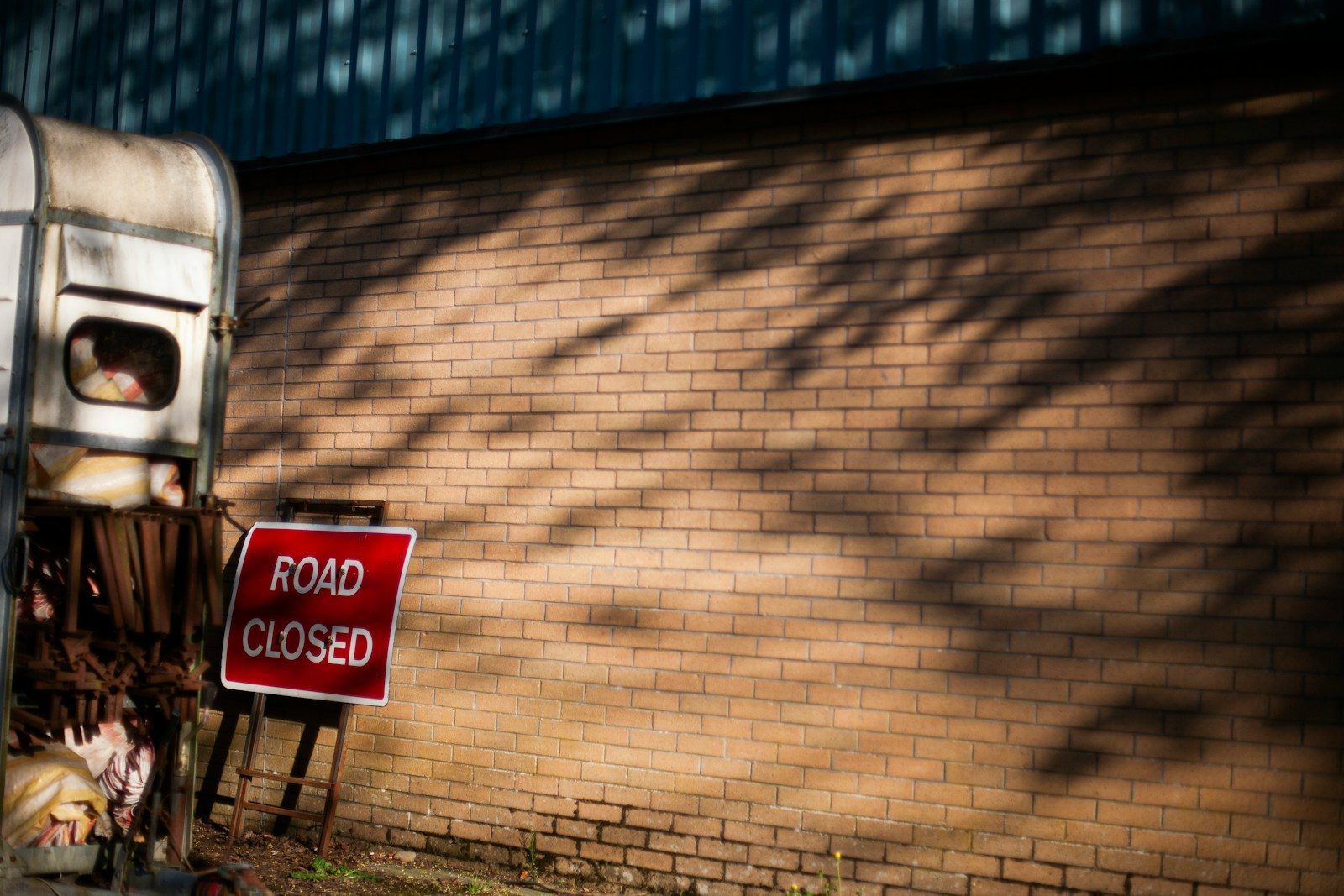 A road closed sign in front of a brick wall.